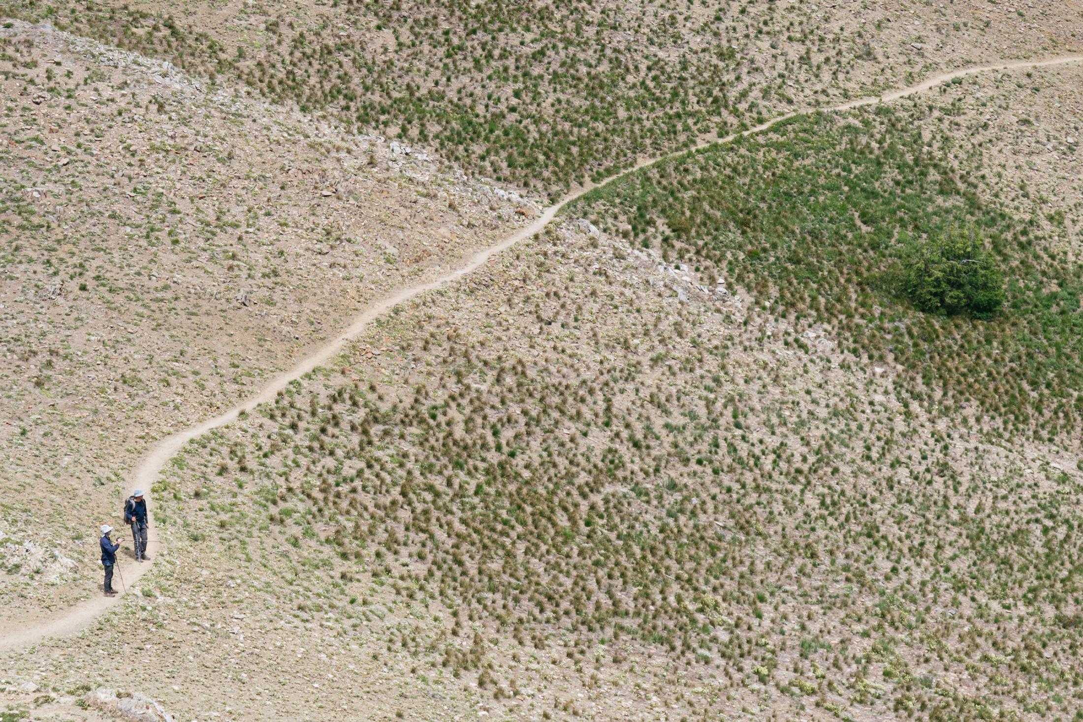 Two figures on a trail in a rocky, dusty area
